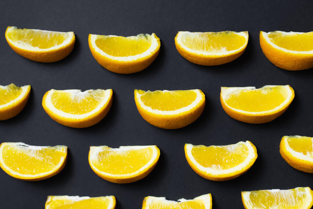 Flat lay of pieces of natural oranges on black background - Foto, Imagen
