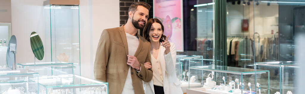 Excited woman pointing at showcase near boyfriend in jewelry shop, banner  - Foto, immagini