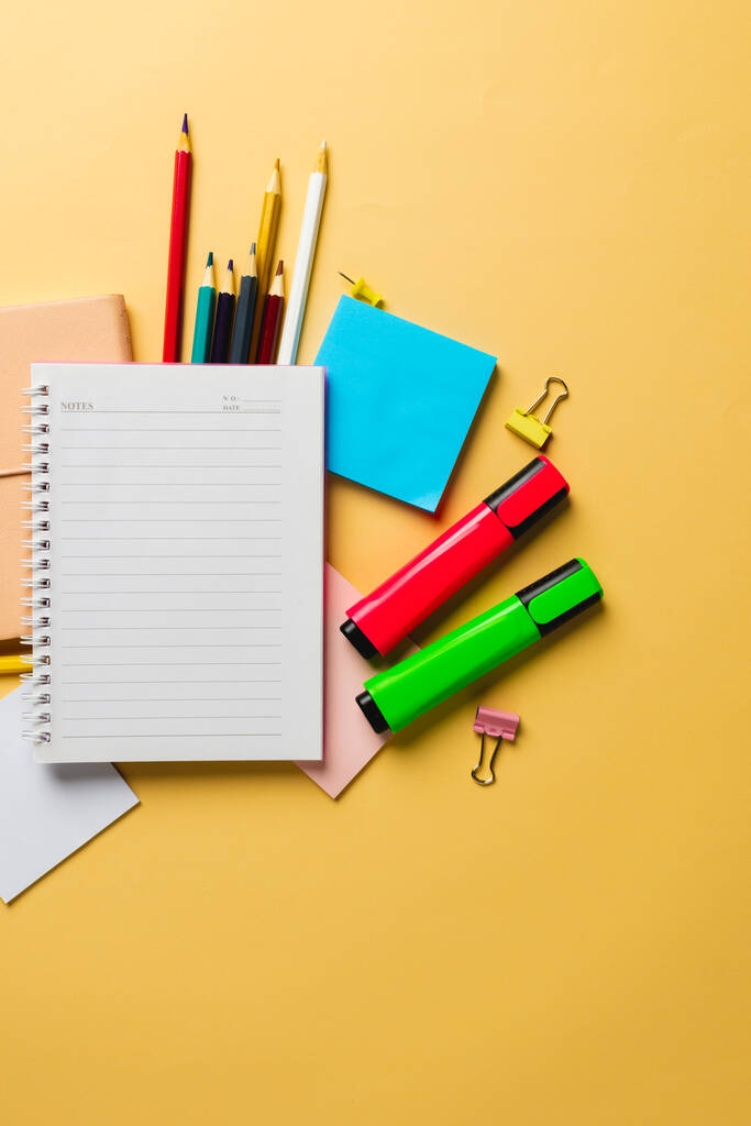 Vertical composition of notebook with copy space and school equipment on yellow surface. School equipment, tools and creativity concept. - Photo, Image