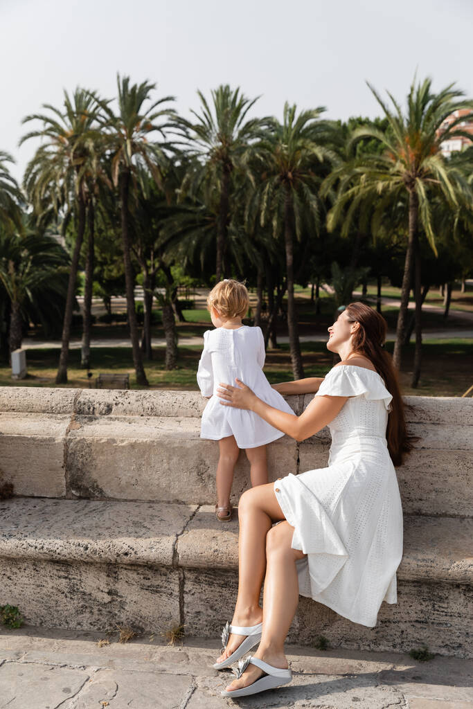 Жінка в літній сукні торкається дитини на мосту Пуенте Дель Мар у Валенсії. - Фото, зображення