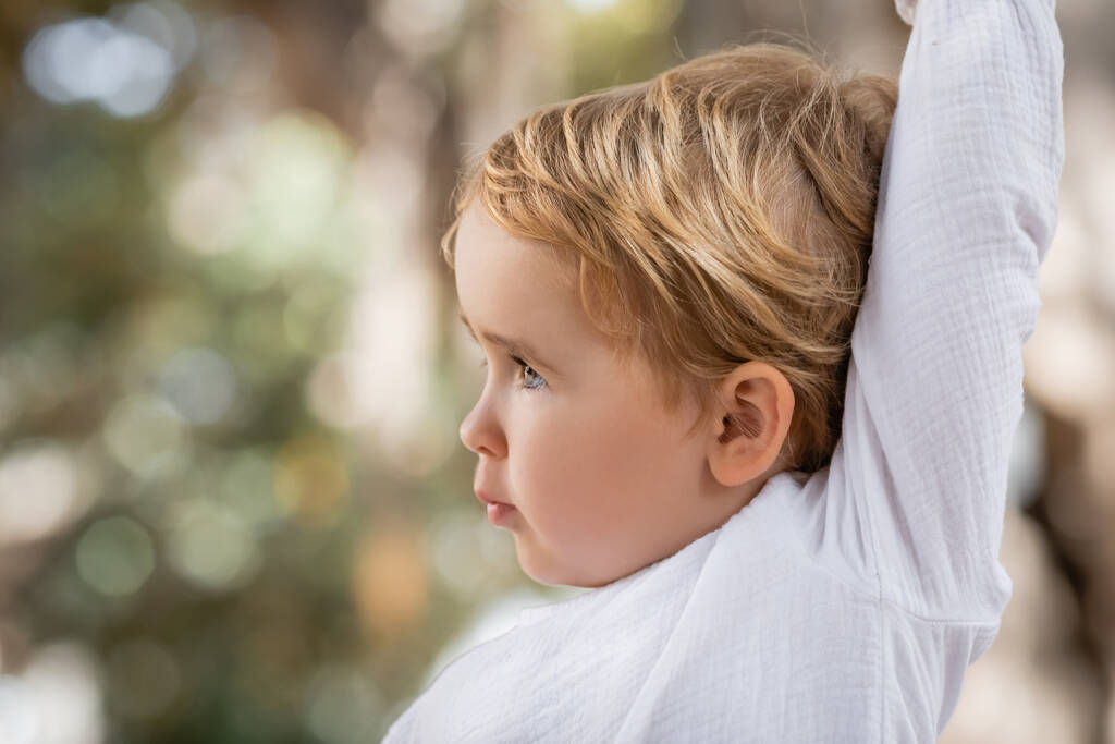 Side view of toddler girl with raising hand outdoors  - Valokuva, kuva