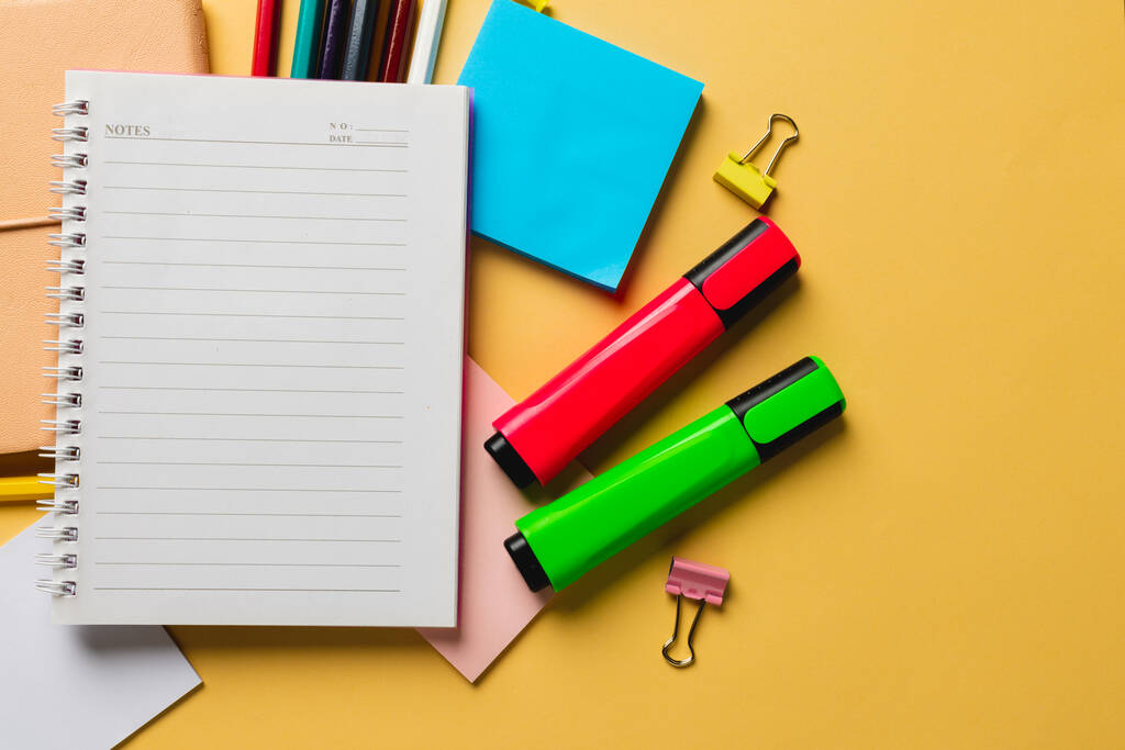 Samenstelling van notebook met kopieerruimte en schoolmateriaal op geel oppervlak. Schooluitrusting, gereedschap en creativiteit. - Foto, afbeelding