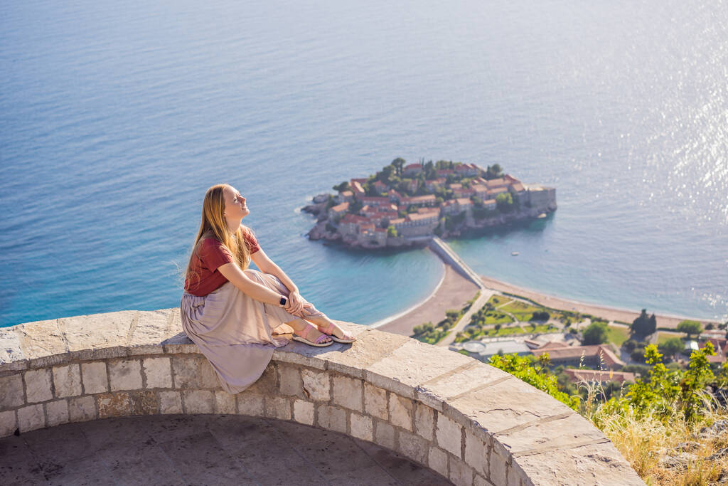 Női turista a háttérben gyönyörű kilátás nyílik a sziget Szent István, Sveti Stefan a Budva Riviérán, Budva, Montenegró. Utazás Montenegróba koncepció. - Fotó, kép