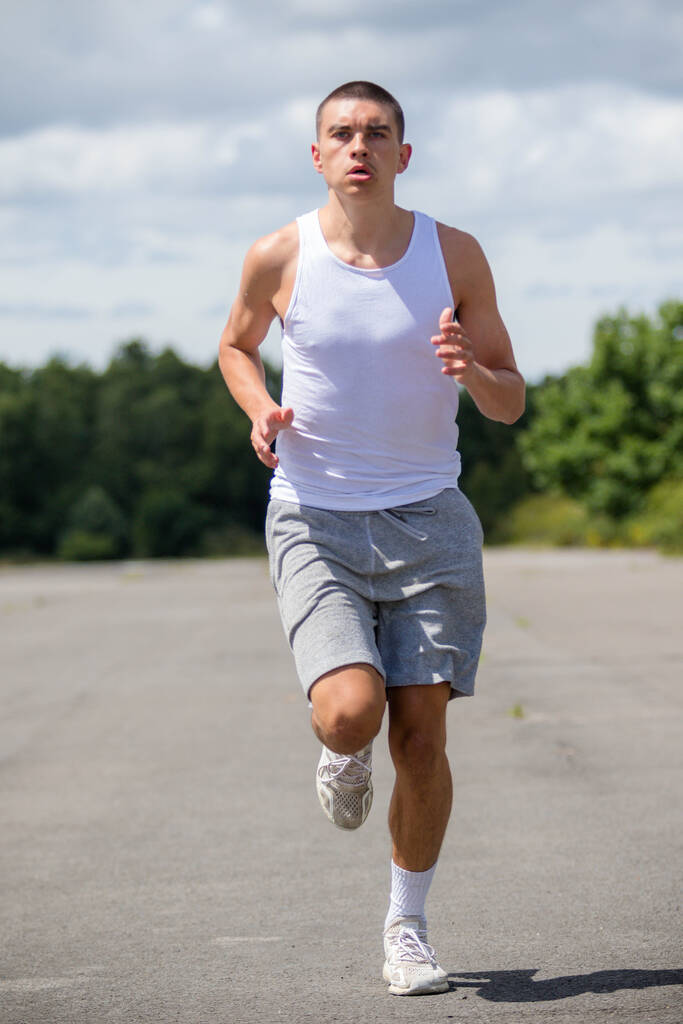 A Nineteen Year Old Teenage Boy Jogging In A Public Park - 写真・画像
