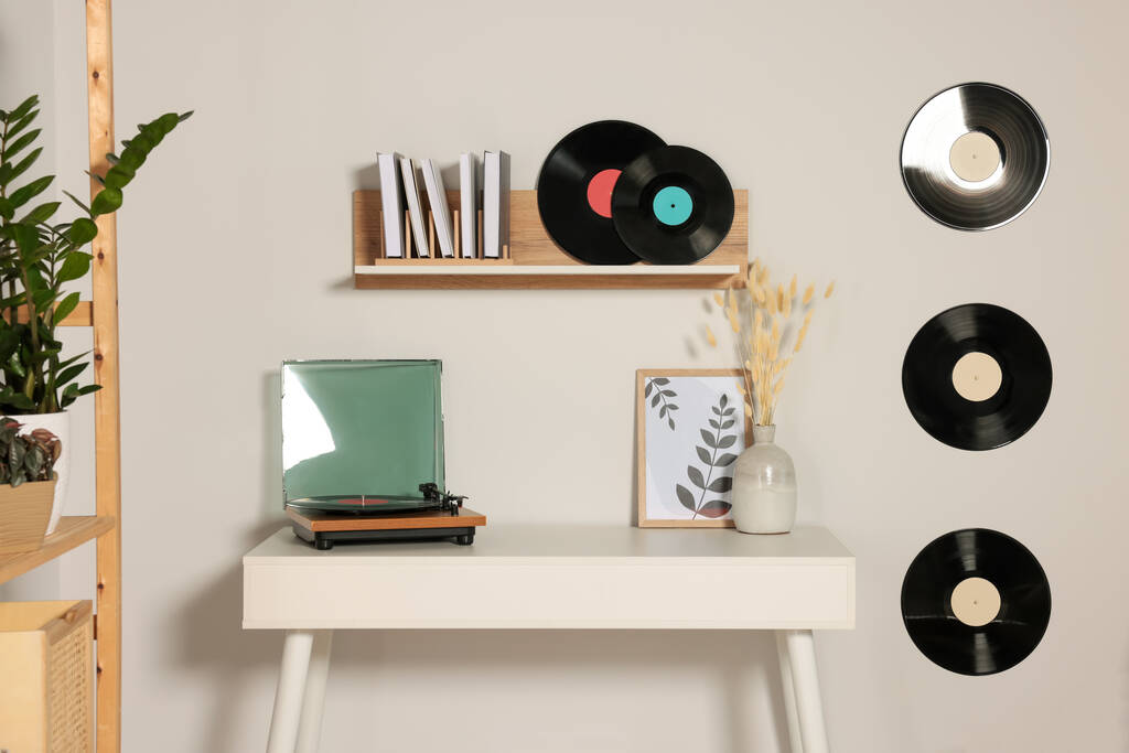 Mesa y elegante tocadiscos cerca de la pared blanca decorada con discos de vinilo - Foto, imagen