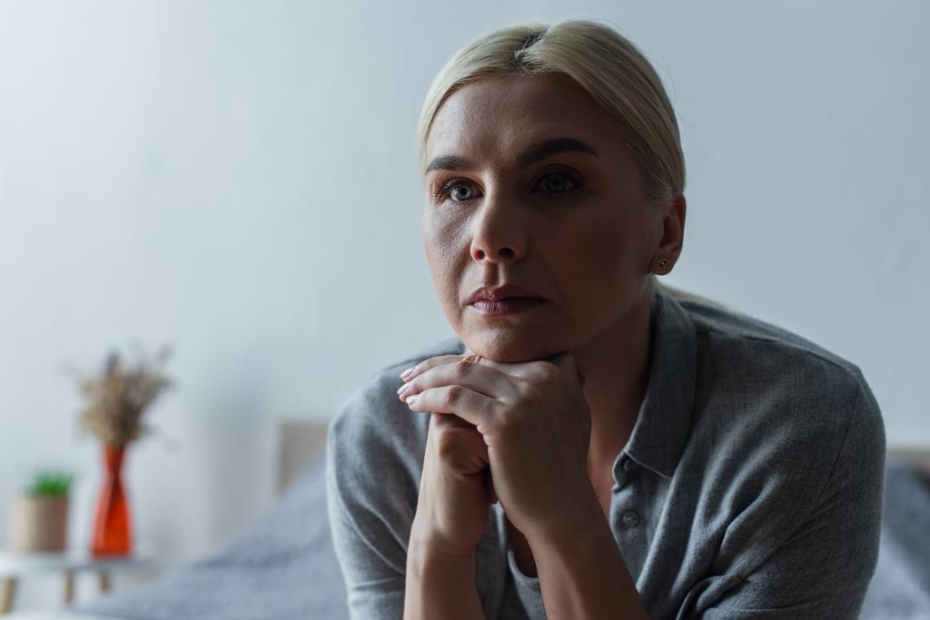 upset blonde woman with menopause looking away in bedroom  - Fotó, kép
