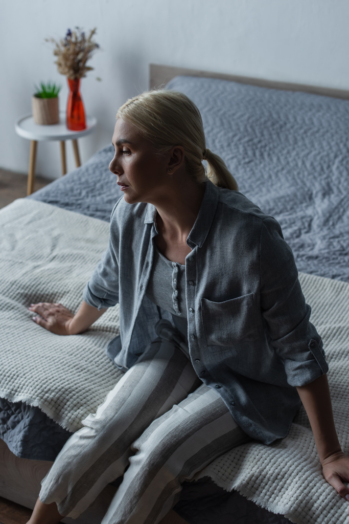 депресивна блондинка з менопаузою сидить на ліжку вдома
 - Фото, зображення
