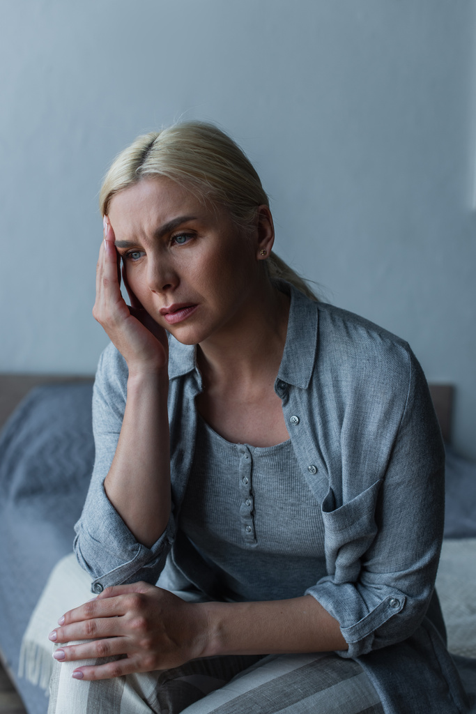 Erschöpfte blonde Frau mit Wechseljahren leidet unter Kopfschmerzen im Schlafzimmer - Foto, Bild