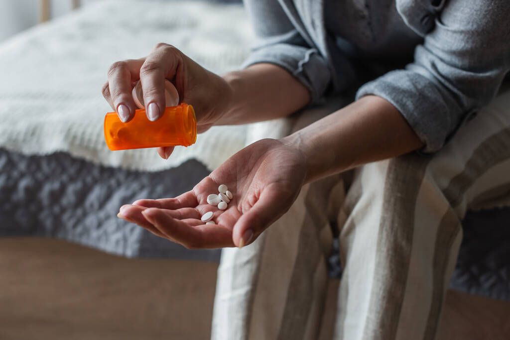 vista ritagliata della donna con la menopausa in possesso di bottiglia e versando pillole in mano - Foto, immagini