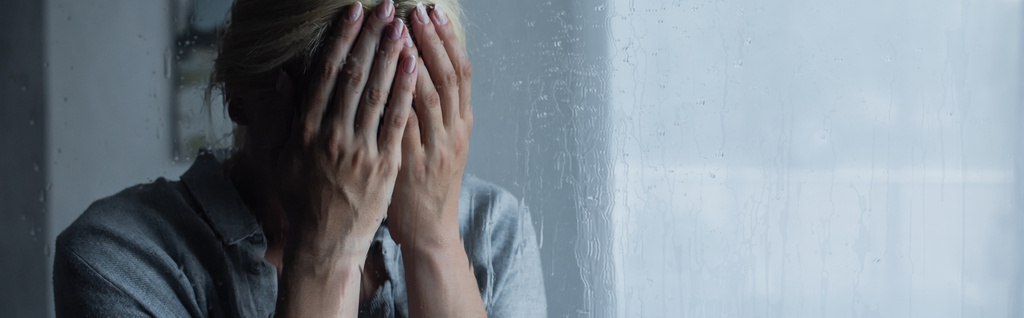 depressed blonde woman covering face behind wet window with rain drops, banner - Photo, Image