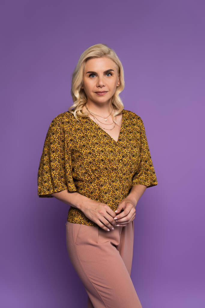 pretty and blonde woman in blouse posing isolated on purple  - Foto, Bild