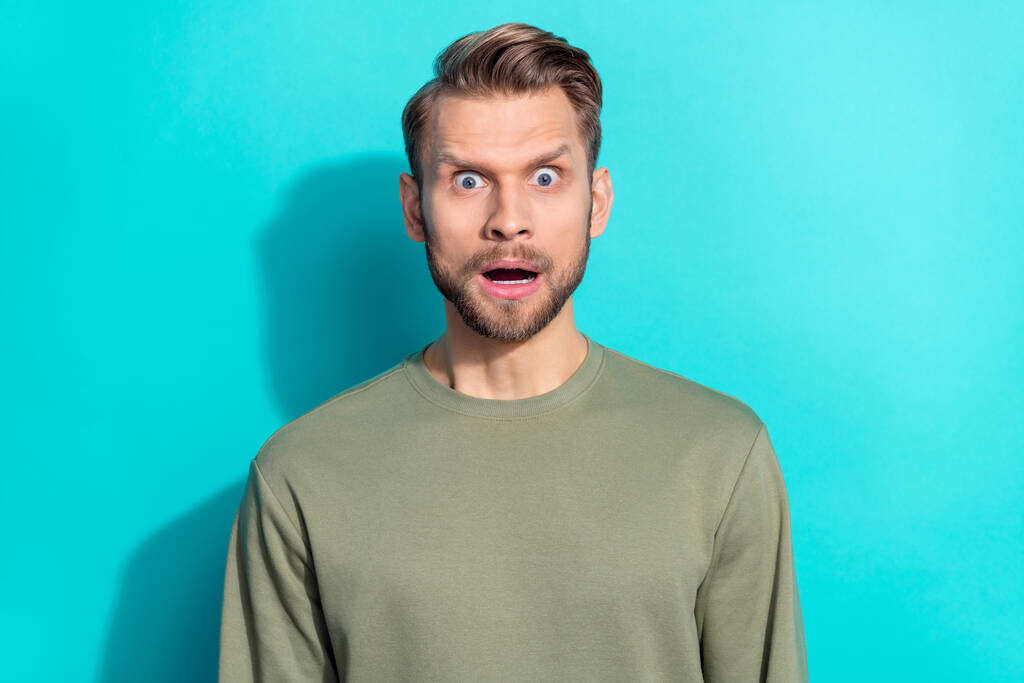 Φωτογραφία του Millennial ξανθιά θυμωμένος άντρας φορούν χακί πουλόβερ που απομονώνονται σε teal φόντο χρώμα. - Φωτογραφία, εικόνα