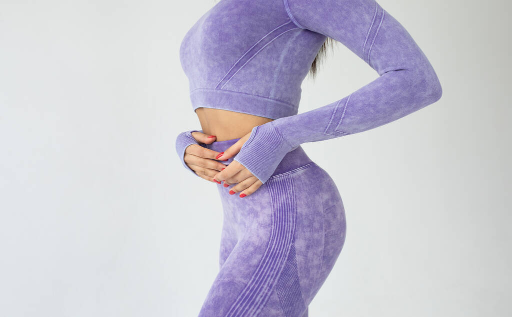 young fit african american woman in purple sportswear posing on grey background  - Photo, image