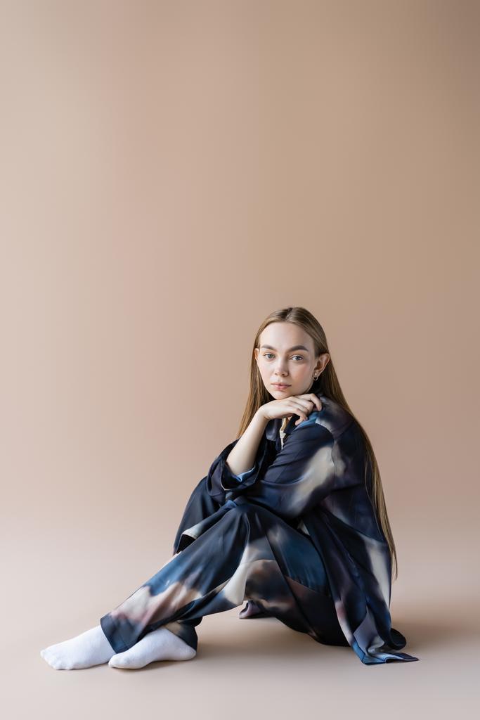 fiatal nő gradiens ruházat ül kézzel közel áll bézs háttér - Fotó, kép