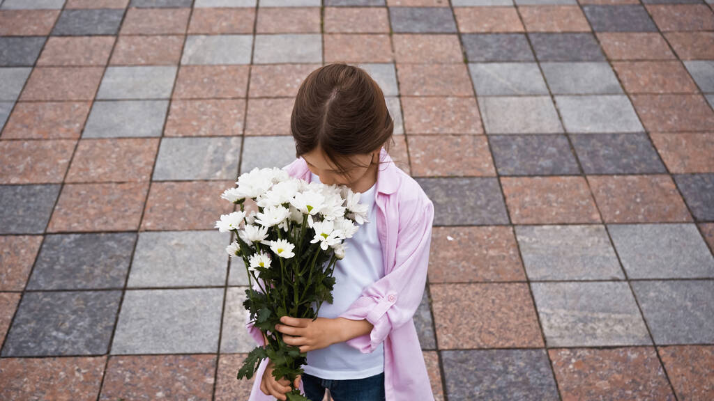 Çiçekler dışarıdayken çocukların koklamasını yüksek açılı görmek - Fotoğraf, Görsel