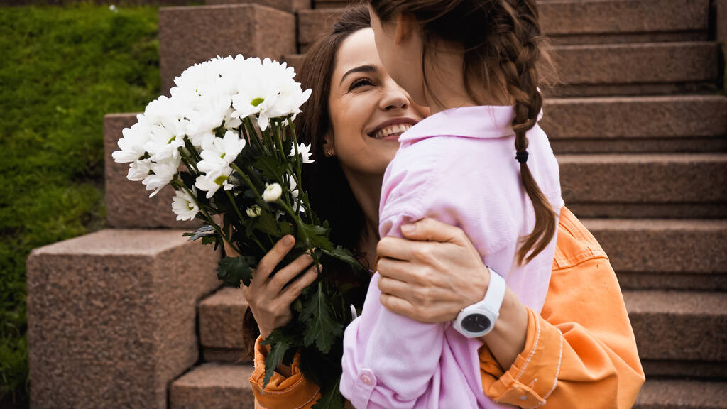 happy mother receiving bouquet of white flowers from daughter  - Foto, Imagem