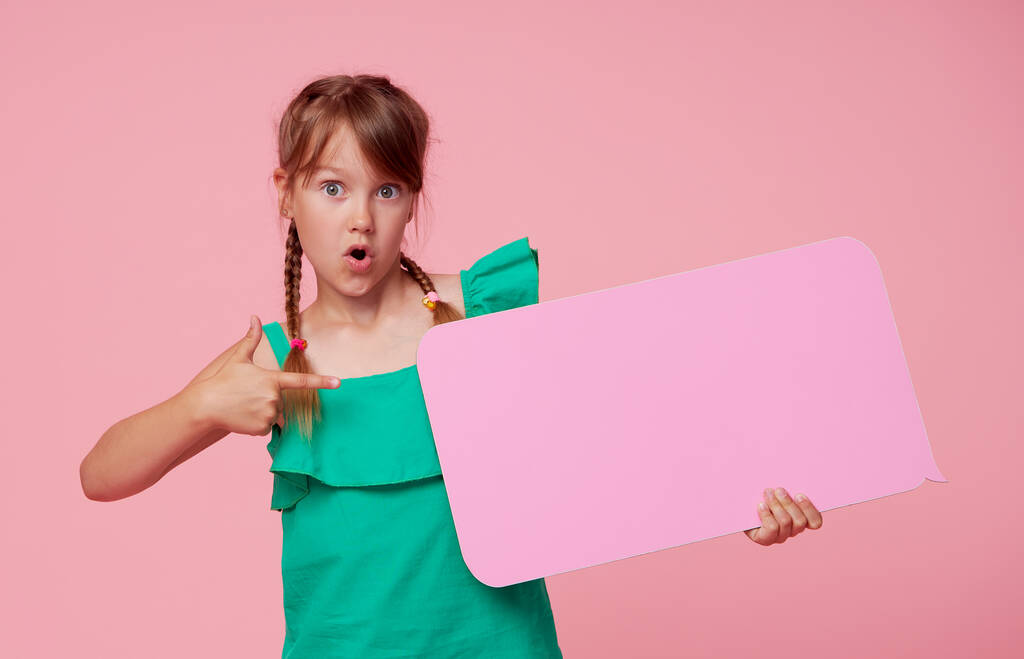 Urocza dziewczynka śmieje się trzymając tablicę z pustą przestrzenią na tekst. Reklama produktów dla dzieci oraz ogłoszenie rabatów i sprzedaży - Zdjęcie, obraz