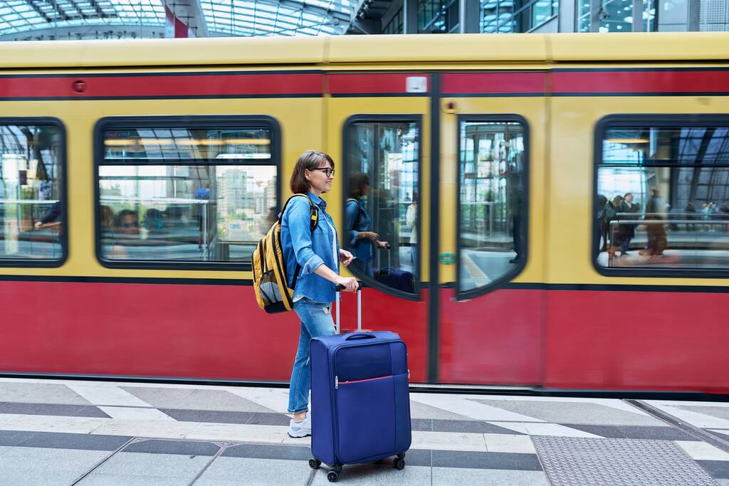 Woman with backpack suitcase at railway station. Female passenger with luggage on platform against background of train. Passenger transport, transportation, trip, journey, travel, people concept - Φωτογραφία, εικόνα