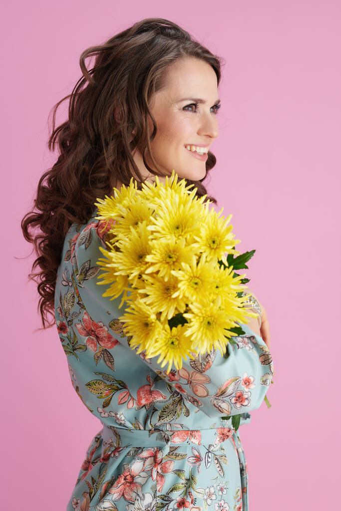 happy elegant female in floral dress with yellow chrysanthemums flowers isolated on pink. - Foto, immagini