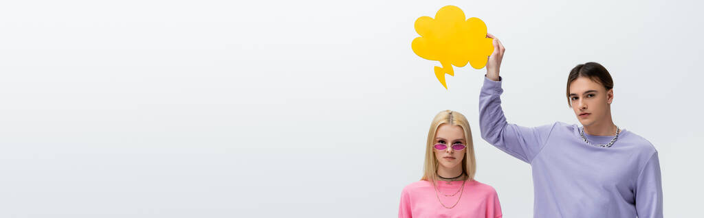 Stylish man holding thought bubble above girlfriend in sunglasses isolated on grey, banner  - Foto, immagini