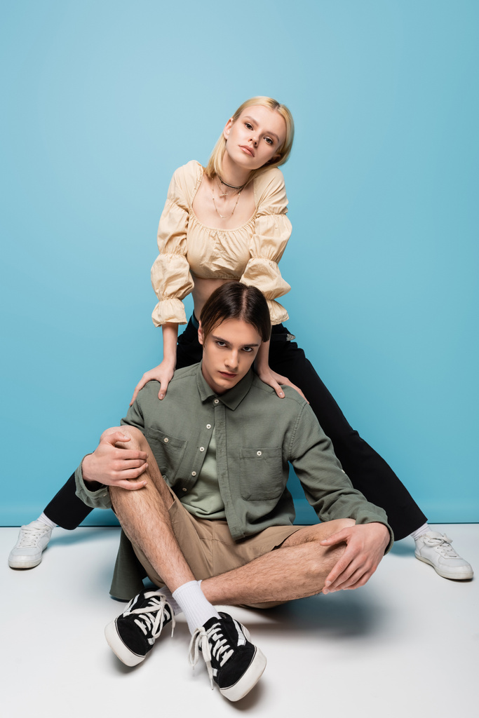 Stylish young couple in sneakers posing on blue background - Foto, afbeelding