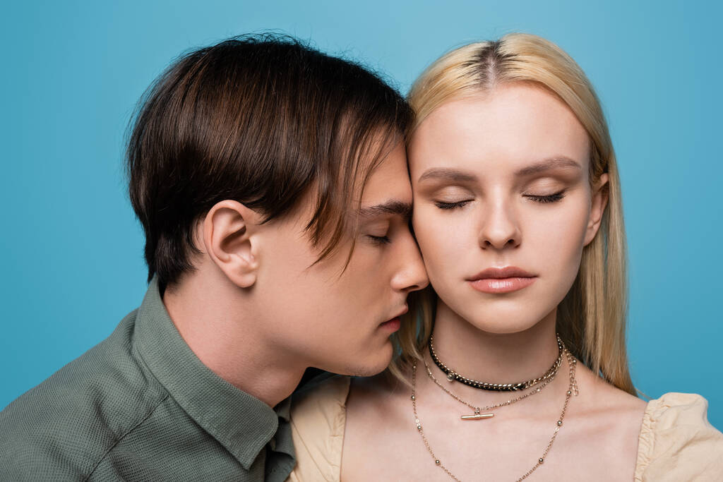 Jovem casal com olhos fechados de pé isolado em azul  - Foto, Imagem