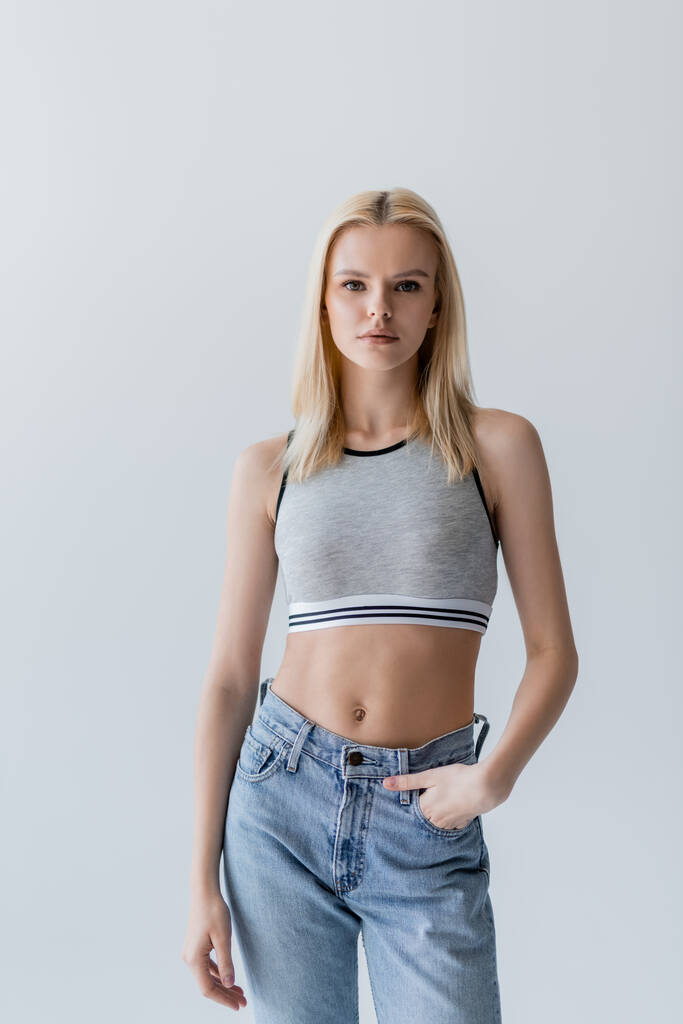 Pretty blonde woman in jeans and top standing isolated on grey  - Foto, immagini