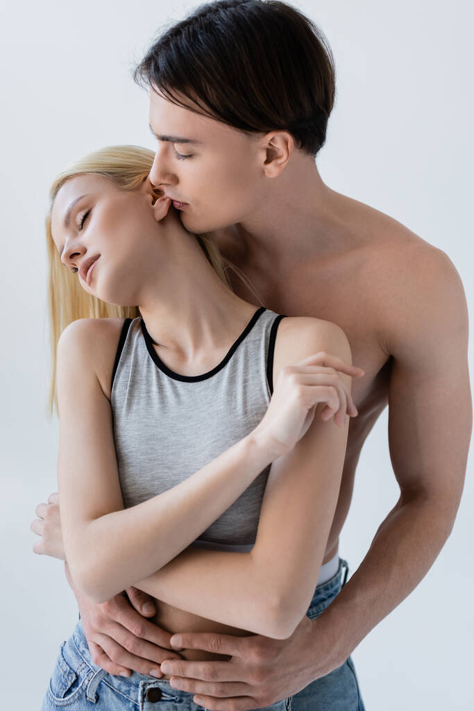 Shirtless man kissing girlfriend in top isolated on grey  - Foto, afbeelding