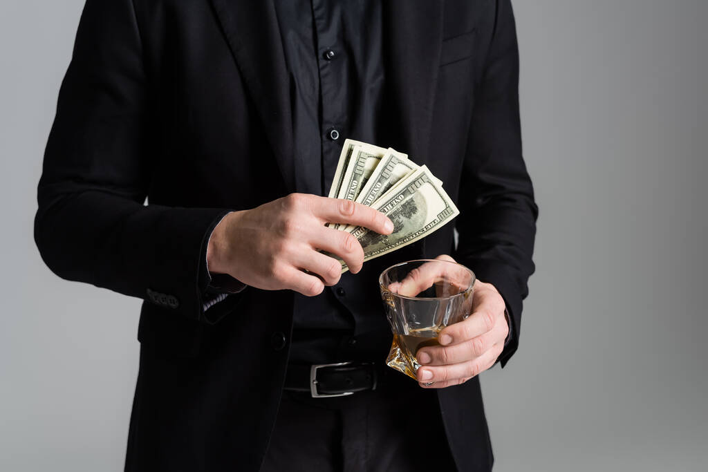 cropped view of man in black formal wear with whiskey and dollars isolated on grey - Φωτογραφία, εικόνα