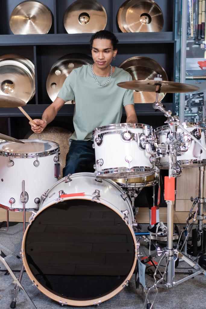 Cliente afroamericano tocando batería en tienda de música  - Foto, Imagen