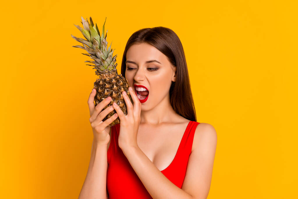 Fotografie hladové legrační dáma oblečený bodysuit kousání čerstvé ananas izolované žluté barvy pozadí. - Fotografie, Obrázek