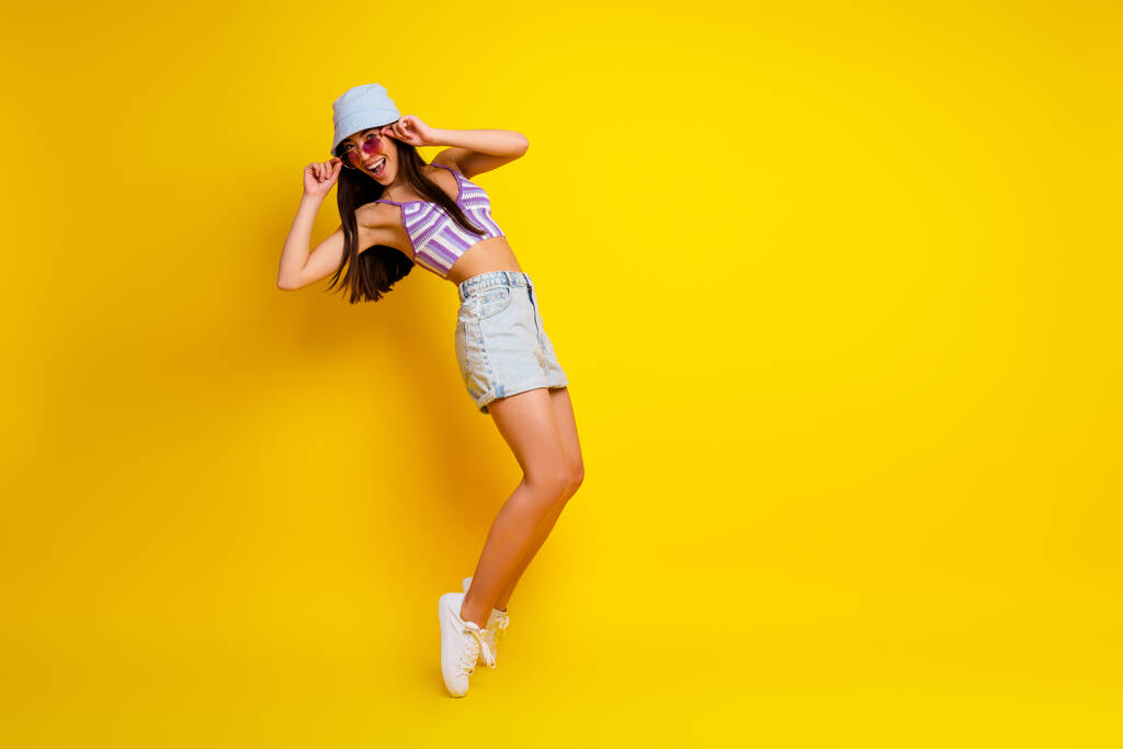 Full length photo of pretty cool lady wear striped crop top cap dark spectacles dancing empty space isolated yellow color background. - Valokuva, kuva