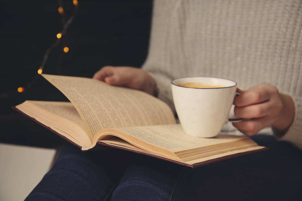 Mujer con taza de libro de lectura de café en casa, primer plano
 - Foto, imagen