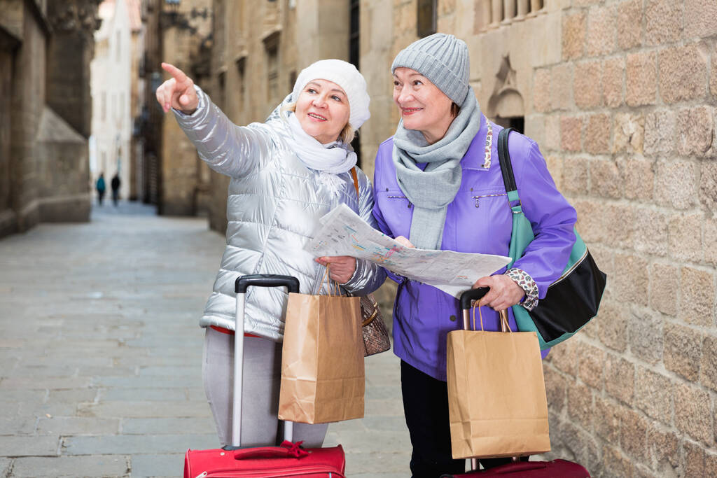 Boldog érett hölgyek utazók bőröndökkel látogassa meg Európa város látnivalóit térképpel - Fotó, kép