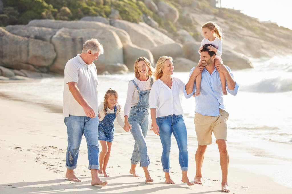 Több generációs család fogja egymás kezét és együtt sétálnak a parton. Kaukázusi család két gyerekkel, két szülővel és nagyszülővel, akik élvezik a nyári vakációt. - Fotó, kép