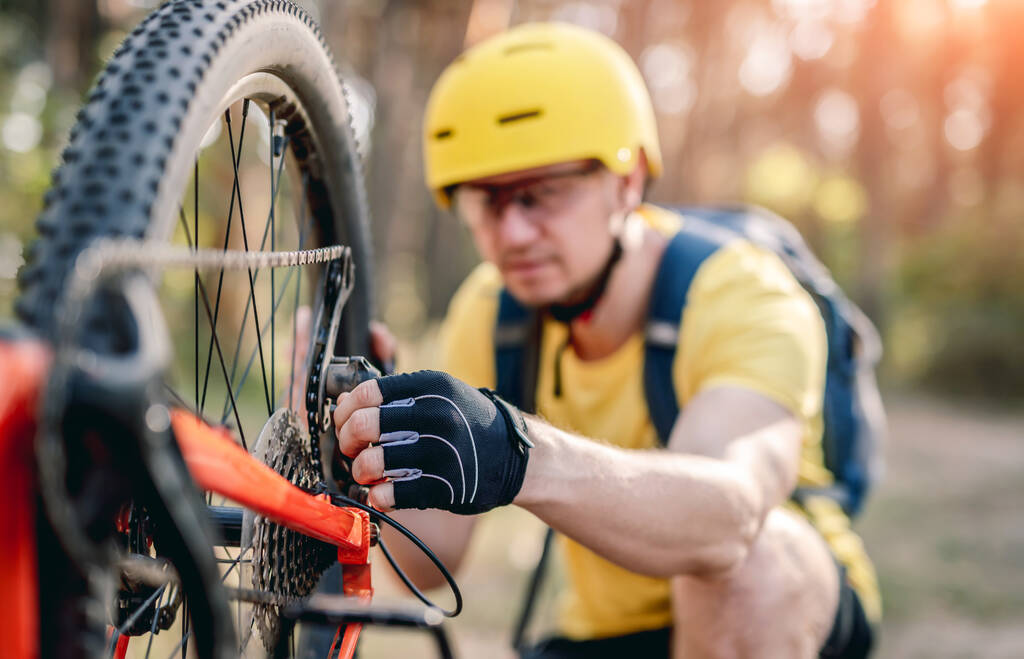 Bisikletçi ormanda ters bisiklette zincirleme arızayı kontrol ediyor. - Fotoğraf, Görsel