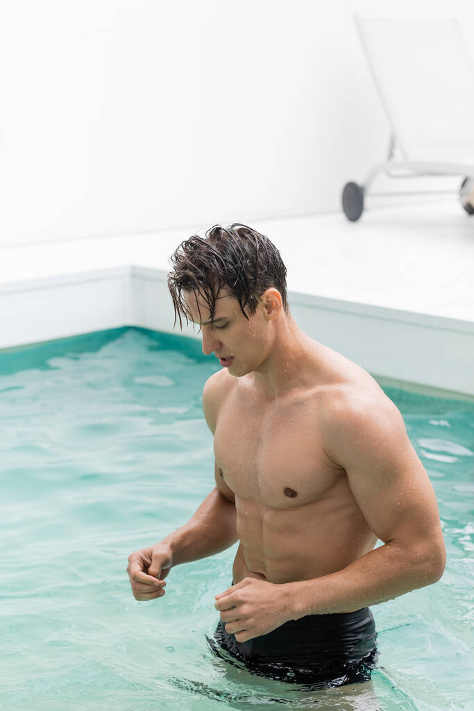 мокрий чоловік з м'язистим торфом в басейні з чистою бірюзовою водою
 - Фото, зображення