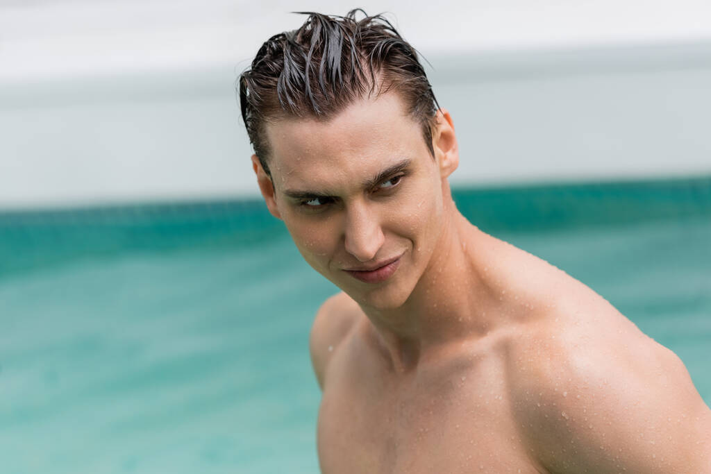 man with wet hair looking away near blurred pool - Foto, Imagen