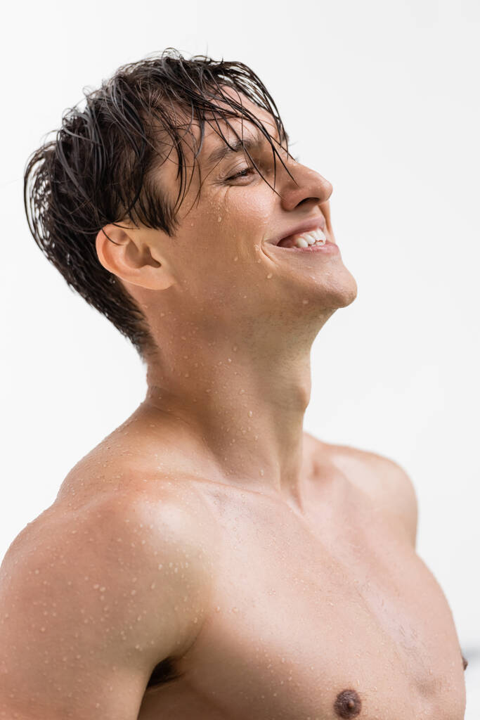 homem molhado e alegre com corpo atlético e pele perfeita isolada em branco - Foto, Imagem