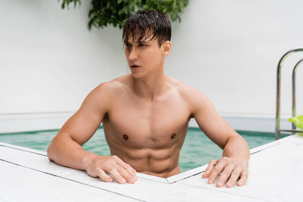 man with sportive torso and wet hair looking away at poolside - Photo, image