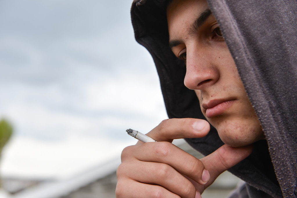 töprengő és zaklató tizenéves fiú fekete kapucnis a dohányzás cigi - Fotó, kép