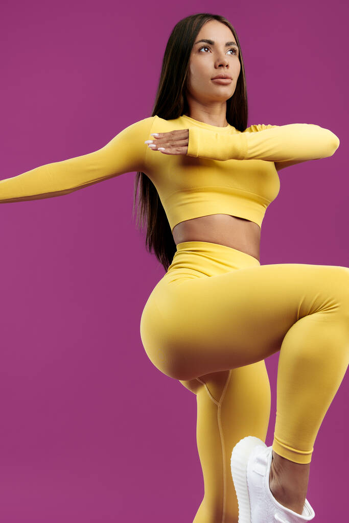 Nahaufnahme Bild von fit junge fit brünette Frau in gelben Sport-Outfit springen über lila Hintergrund - Foto, Bild