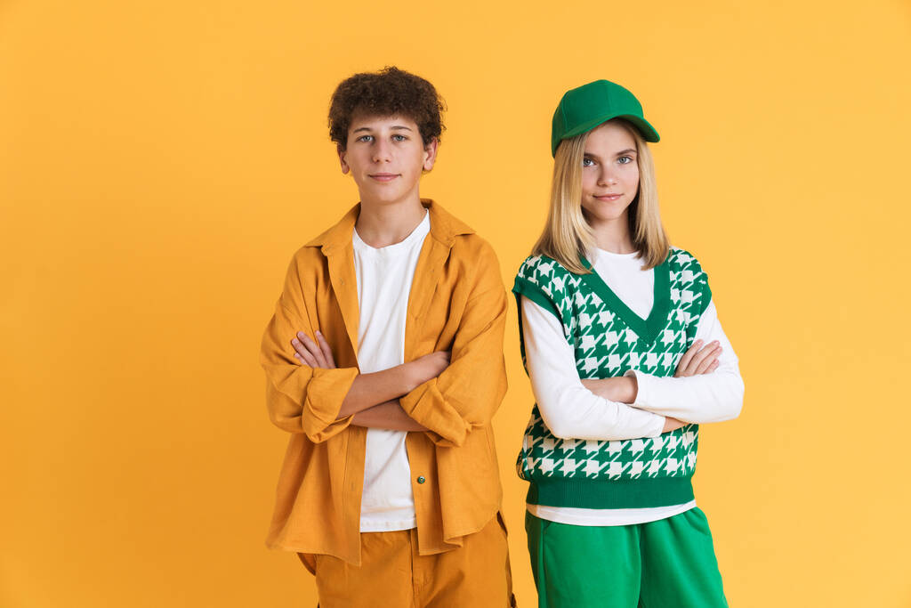 White teenagers looking at camera while posing with arms crossed isolated over yellow wall - Photo, image