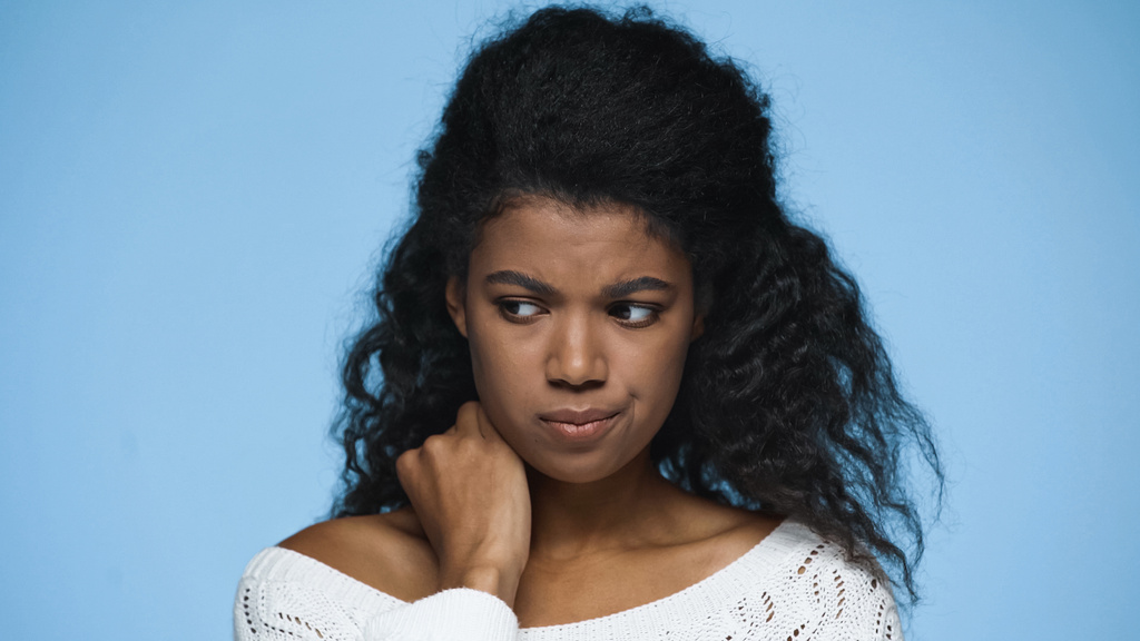 sad african american woman in white knitted sweater looking away isolated on blue - Foto, Imagen