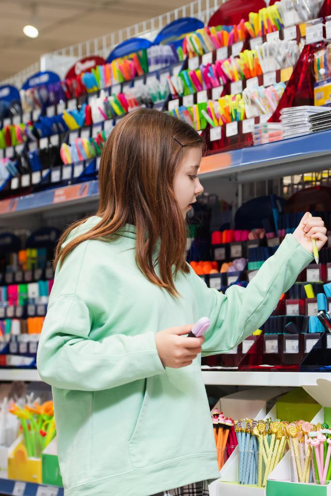 girl choosing school supplies in stationery store - Foto, Imagen