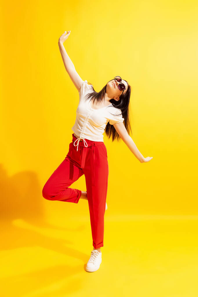 Dancing. Young beautiful woman in summer casual style outfit isolated on bright yellow background. Concept of beauty, art, fashion, youth, healthy lifestyle. Copyspace for ads, text, sales offer. - Valokuva, kuva