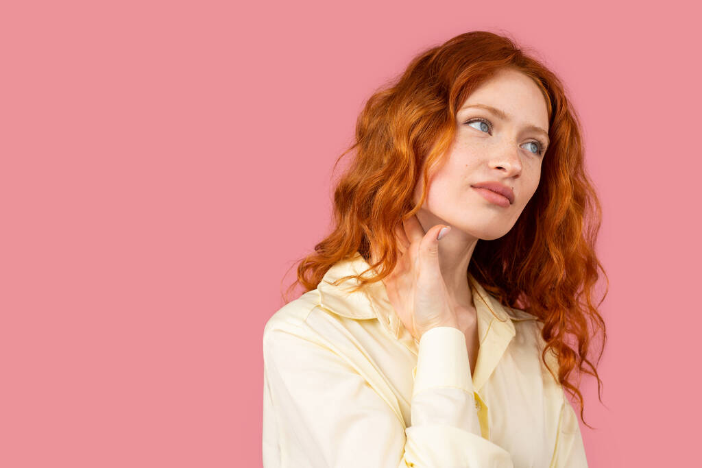 Ritratto di sorprendente giovane donna con capelli ricci rossi e occhi azzurri guardando altrove in piedi su sfondo rosa e copiare lo spazio. Foto di alta qualità - Foto, immagini