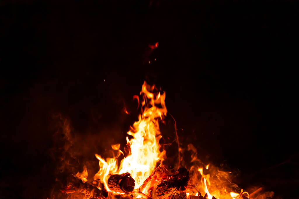 Bruciando scintille calde rosse sorgono da un grande incendio nella notte. Fuoco fiamme scintille sfondo. Abstract buio brillantini fuoco particelle luci. - Foto, immagini