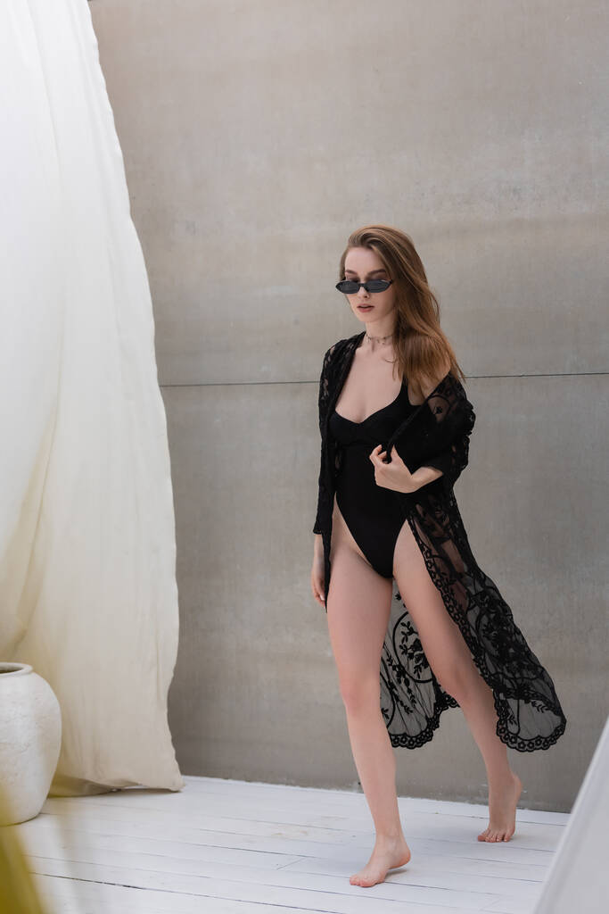 Stylische Frau in Badebekleidung und Sonnenbrille spaziert im Resort  - Foto, Bild