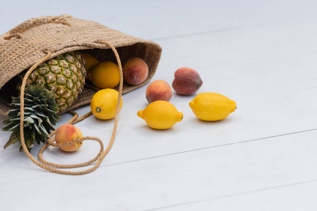 Fresh tropical fruits in straw handbag on floor at resort  - Foto, Imagen